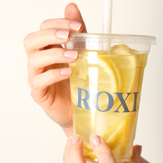 Hand holding a lemon drink with micro french nail design